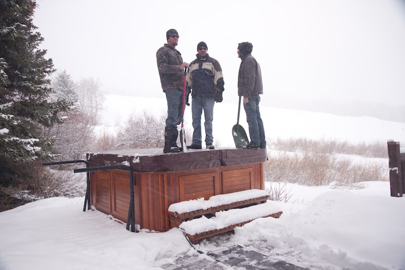 Men staying on the covered hot tub in the winter